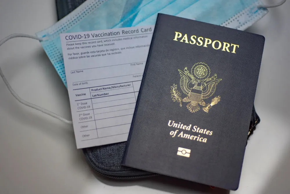 Passport, face mask, and vaccine card on table
